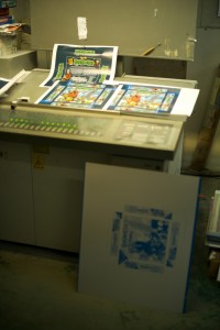 A proofing station, showing both the finished prints, and one of the master plates below.